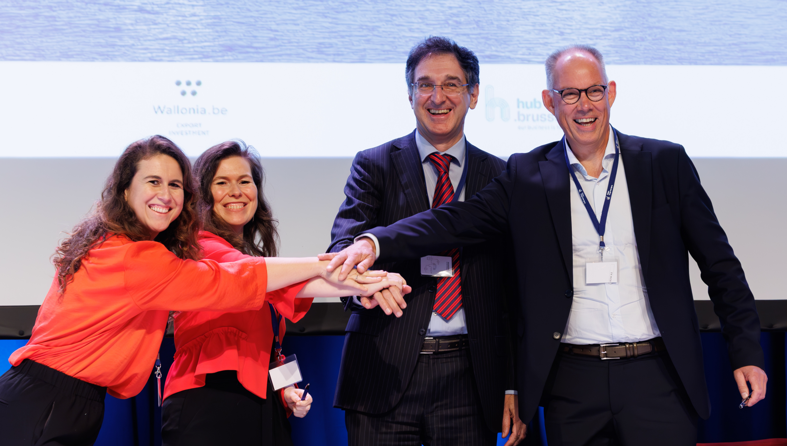 Four participants joining hands at an education event